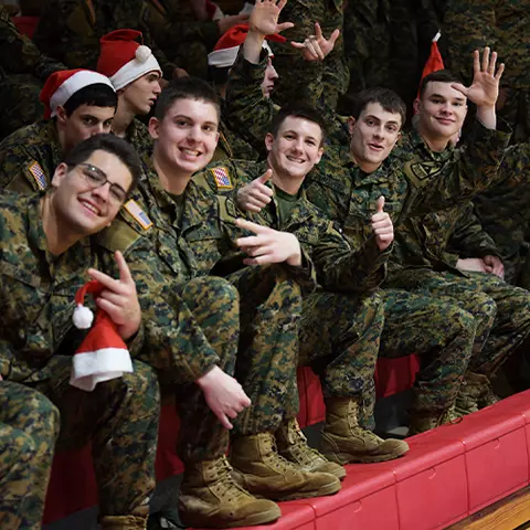 Teenage boys in military uniforms with santa hats laughing and smiling