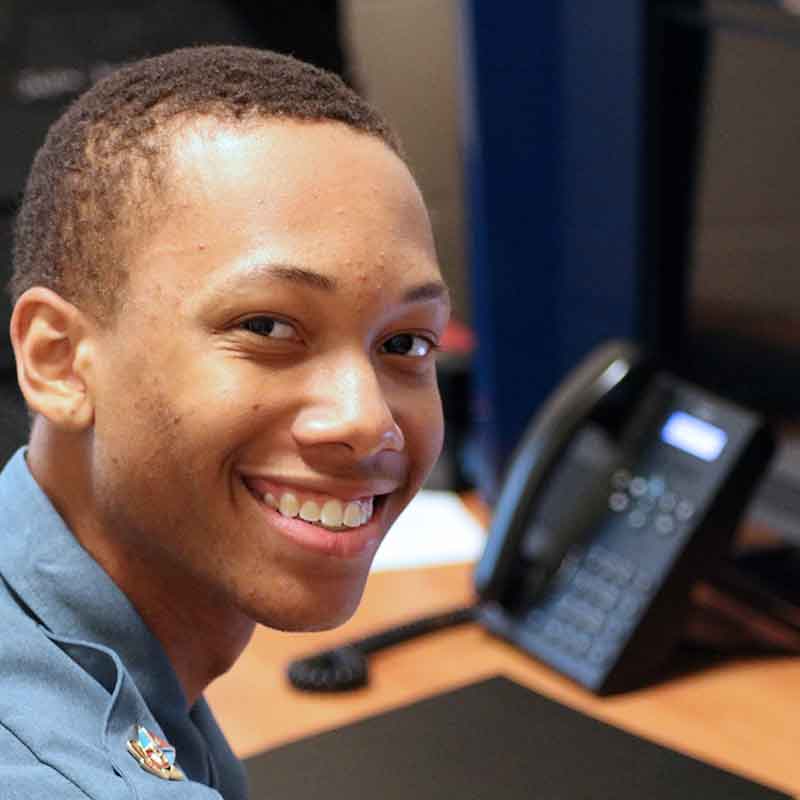 Cadet in barracks room with telephone on desk.