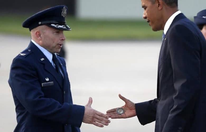 President Barack Obama presents his challenge coin to a service member in a handshake.