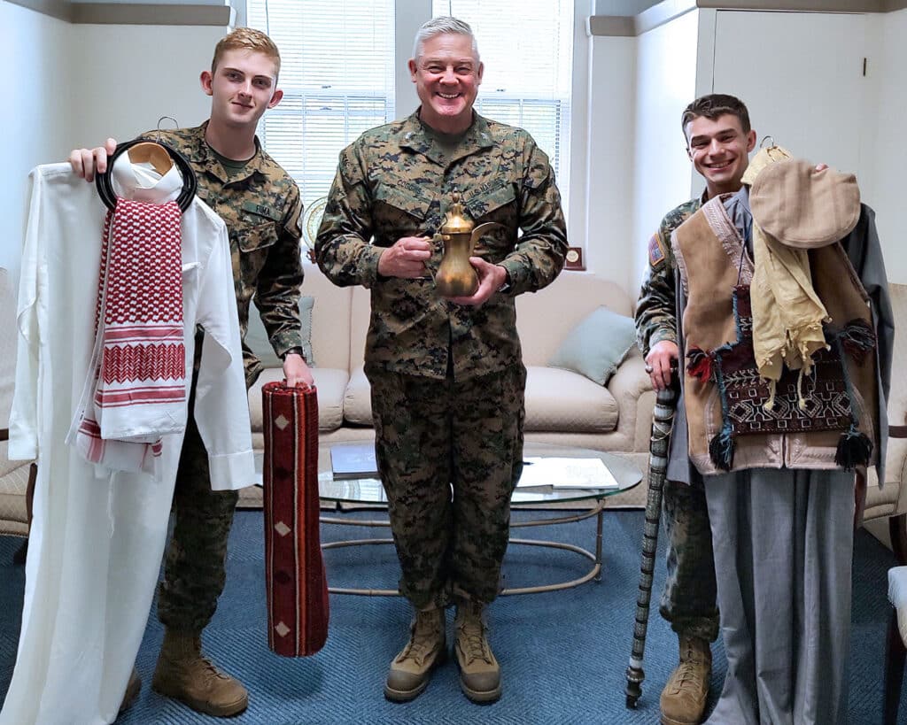 Col. David L. Coggins, USMC (Ret.), presents Cadet Ethan Schroyer (left) and Cadet Jackson Pretus (right) with traditional Bedouin and Pashtu attire and tribal gifts.