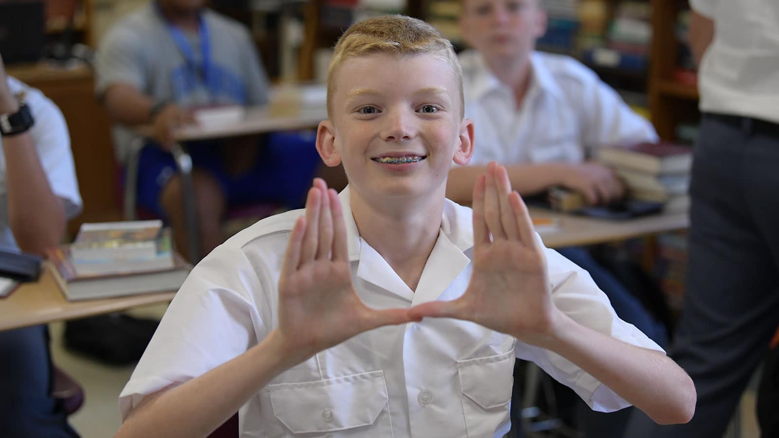 Cadet in class at Fork Union Military Academy making "the U" hand gesture for Fork UNION.