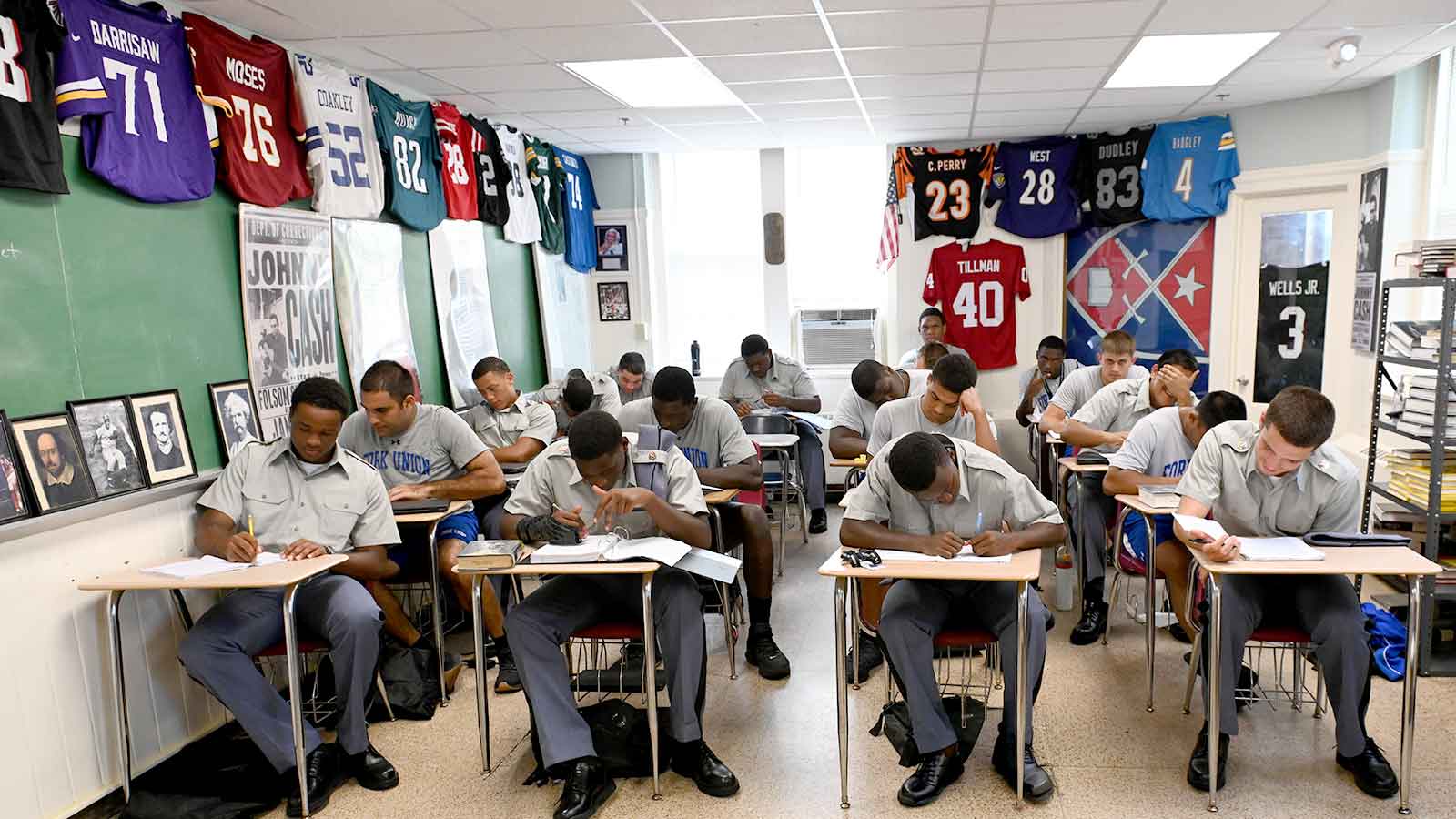 Postgraduate athletes study hard in a classroom displaying the jerseys of previous Fork Union postgraduates who have played in the NFL.