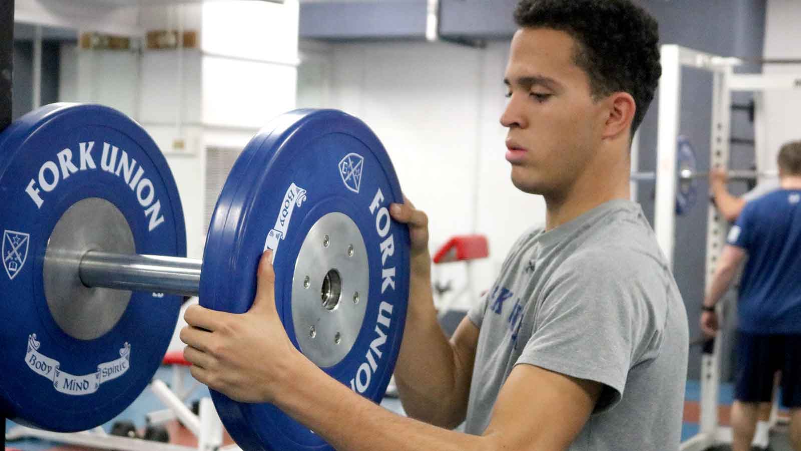 An athlete adds weight to the bar in Fork Union Military Academy's weight room.